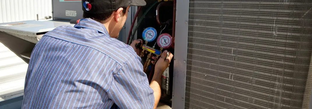HVAC technician servicing a condenser unit in Grand Terrace