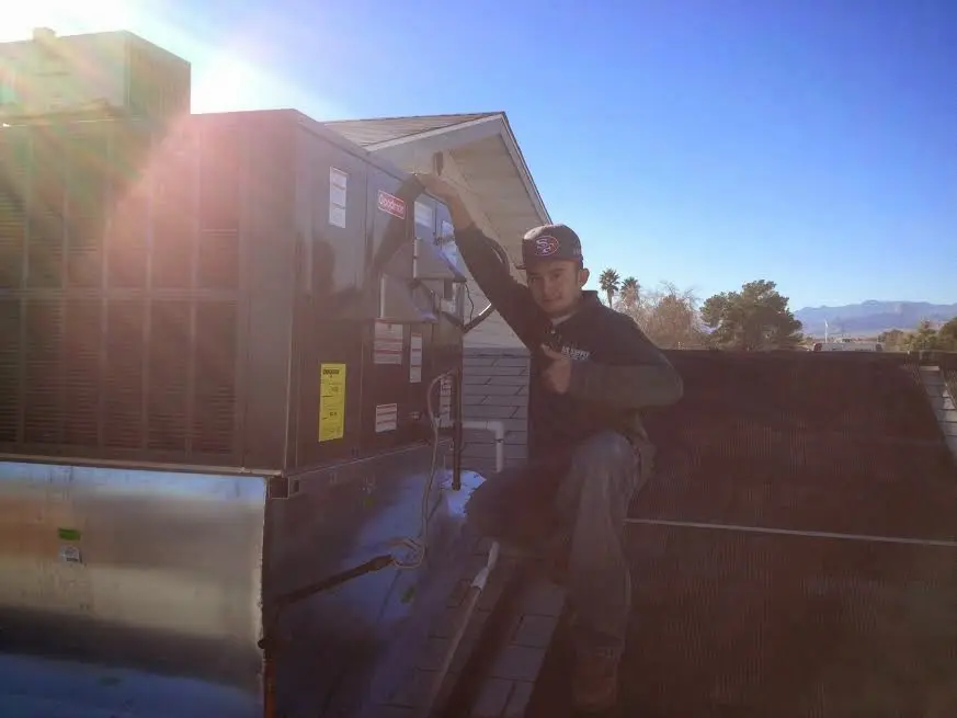 HVAC technician performing Air Duct Repair on a rooftop unit in Grand Terrace
